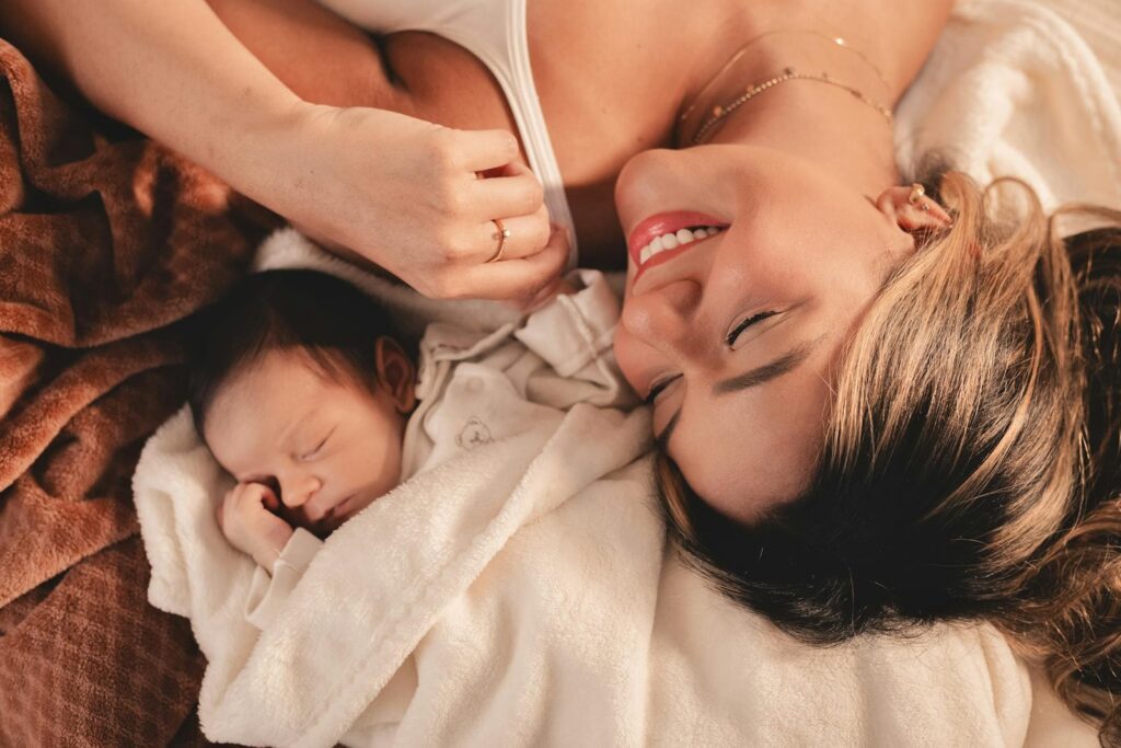 A mother and her newborn baby lying peacefully together in a cozy blanket.