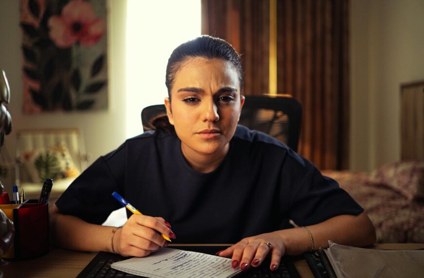 A woman intensely focused on writing notes at her home office desk, deep in concentration.