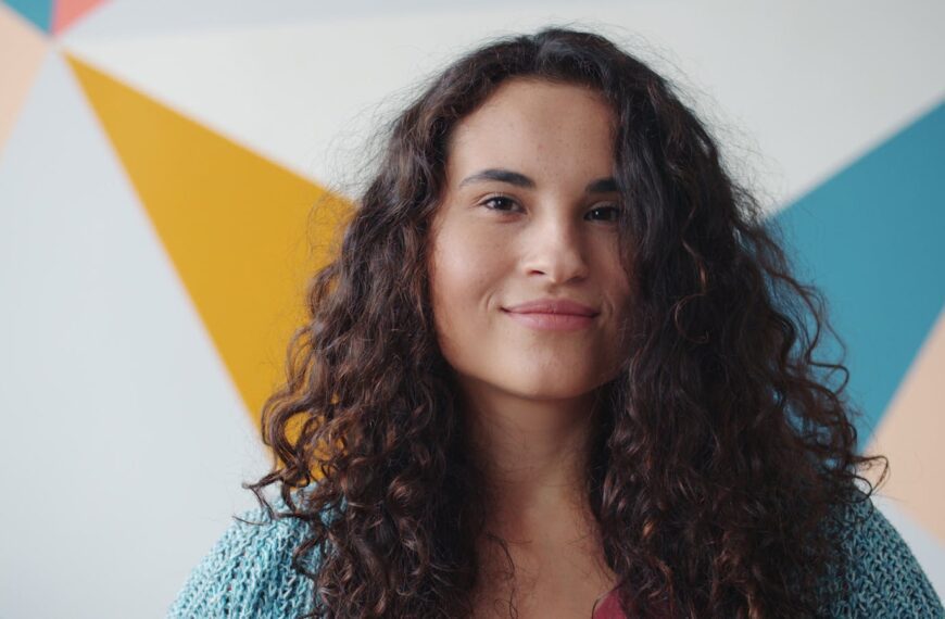 Close-up of a cheerful woman with curly hair against a geometric background. Vibrant and modern.