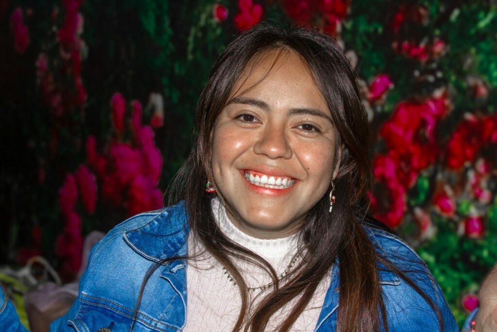 Portrait of a joyful woman smiling warmly with a vibrant floral backdrop.