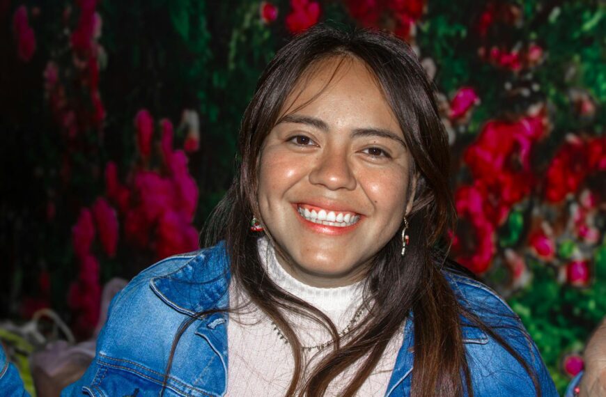 Portrait of a joyful woman smiling warmly with a vibrant floral backdrop.