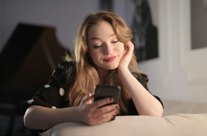 Smiling young woman enjoying leisure time on her smartphone in a cozy living room.