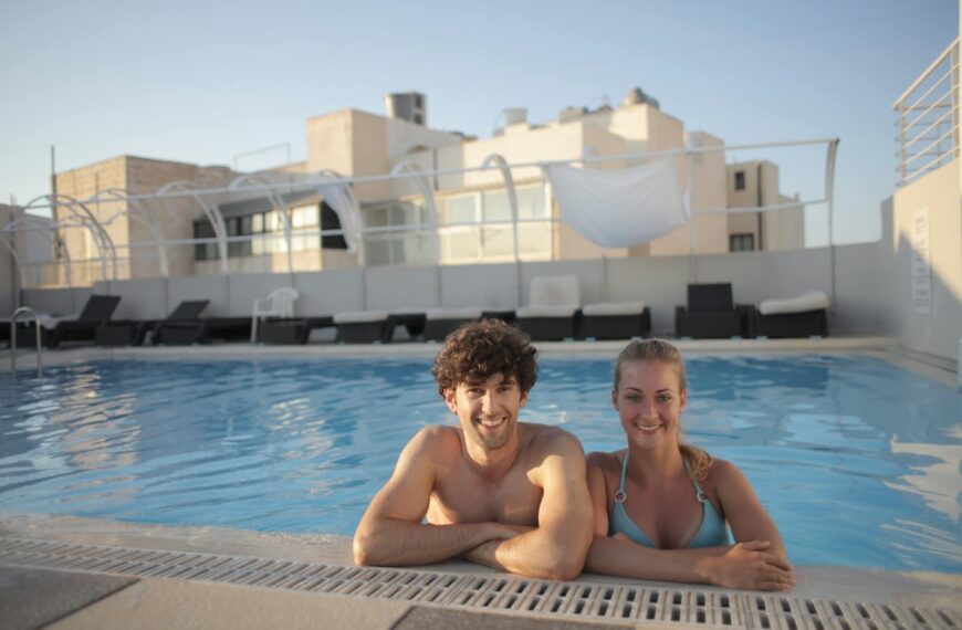 Happy young couple enjoying a sunny day at a tropical resort swimming pool.