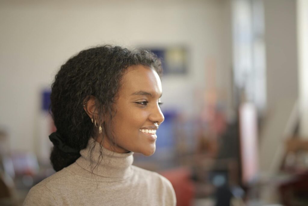Profile of a smiling woman indoors, exuding warmth and positivity in natural light.