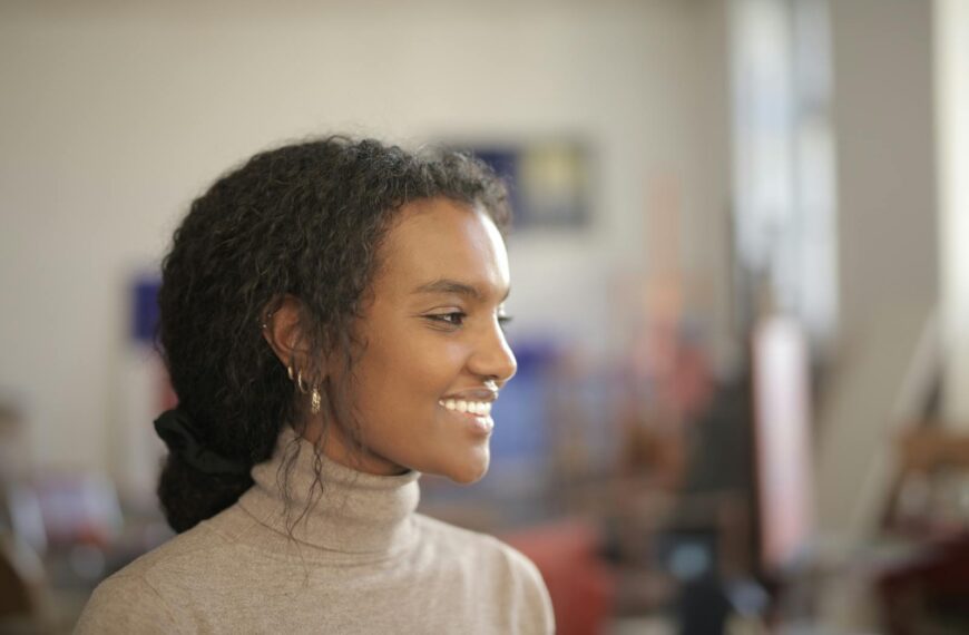 Profile of a smiling woman indoors, exuding warmth and positivity in natural light.