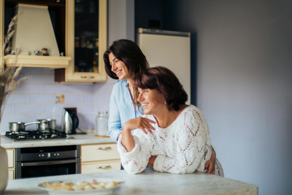 A mother and daughter share a moment of joy and togetherness in their cozy kitchen.