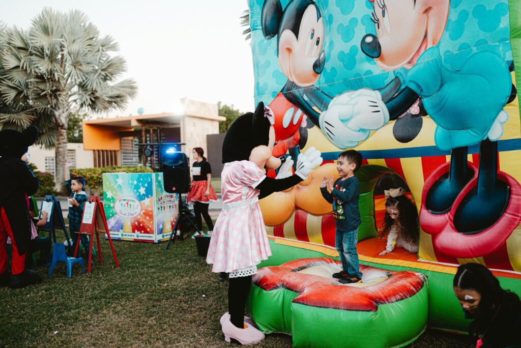 Minnie mouse greets a child on a bouncy castle.