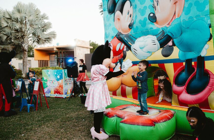 Minnie mouse greets a child on a bouncy castle.