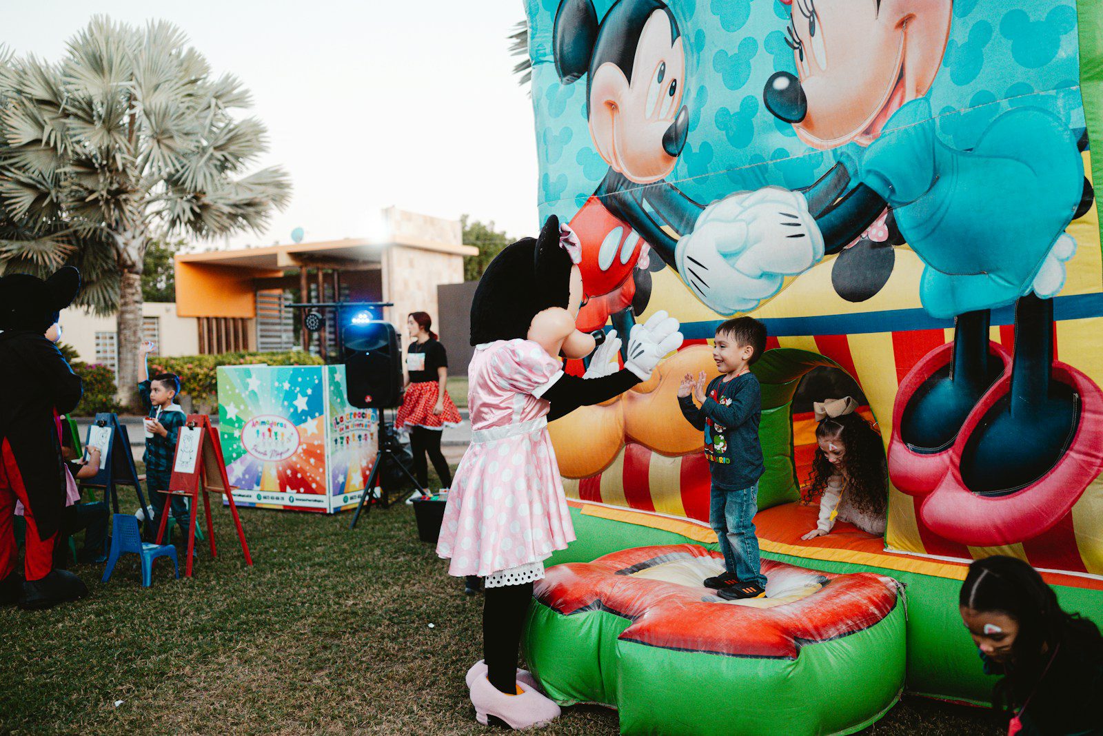 Minnie mouse greets a child on a bouncy castle.