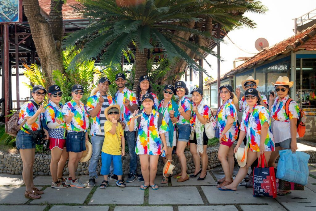 A lively group of adults and a child enjoying a sunny day outdoors in colorful matching shirts.