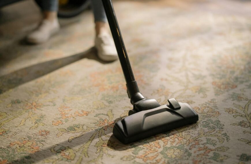 Close-up of a vacuum cleaner on a patterned carpet in a sunlit room, capturing a moment of household cleaning.