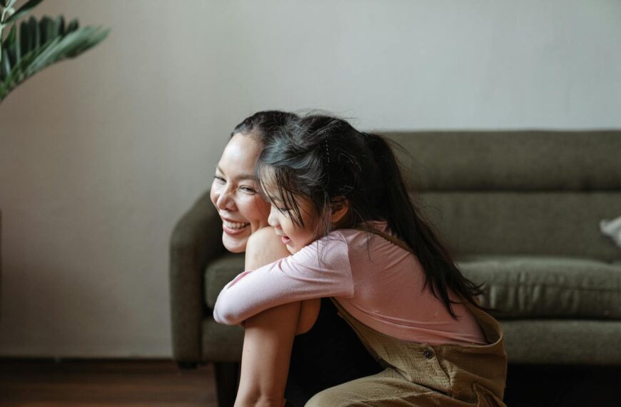 Smiling mother and daughter sharing a warm embrace in a cozy home setting.