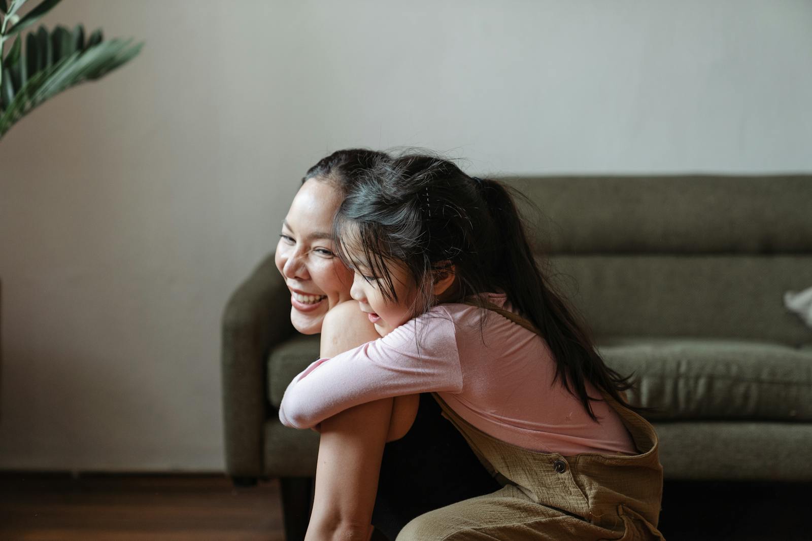 Smiling mother and daughter sharing a warm embrace in a cozy home setting.
