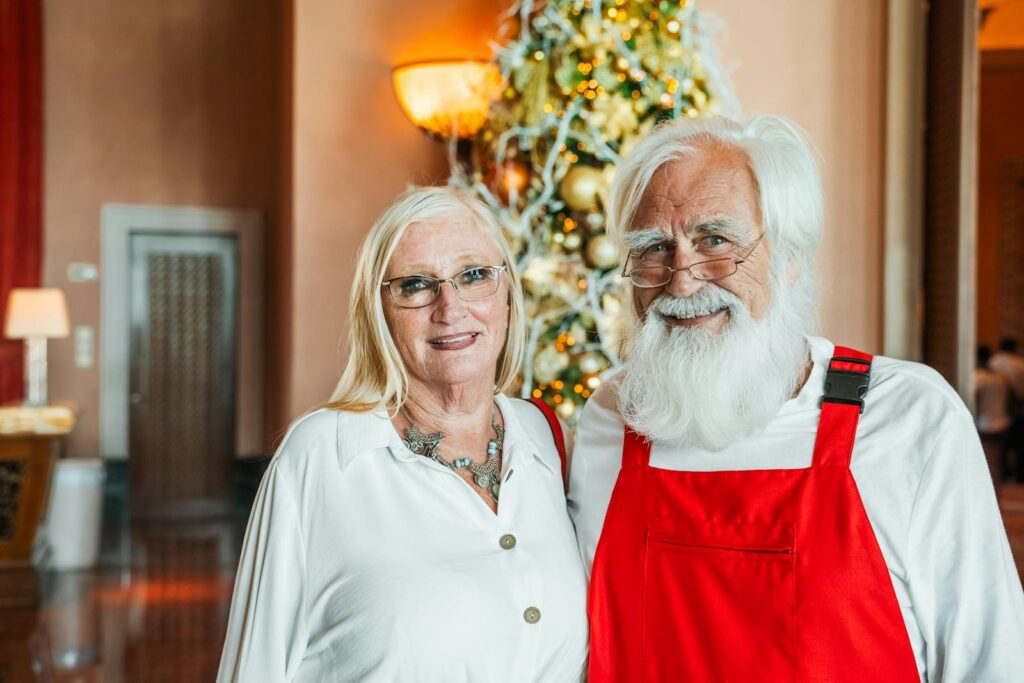 Senior couple smiling in front of a Christmas tree indoors in Dubai, United Arab Emirates.
