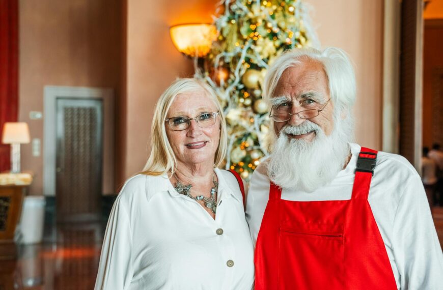 Senior couple smiling in front of a Christmas tree indoors in Dubai, United Arab Emirates.