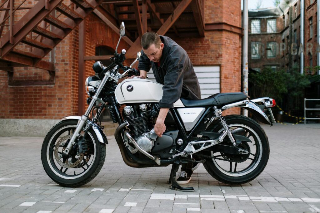 Mechanic examining a Honda CB1100 motorcycle in an urban setting.