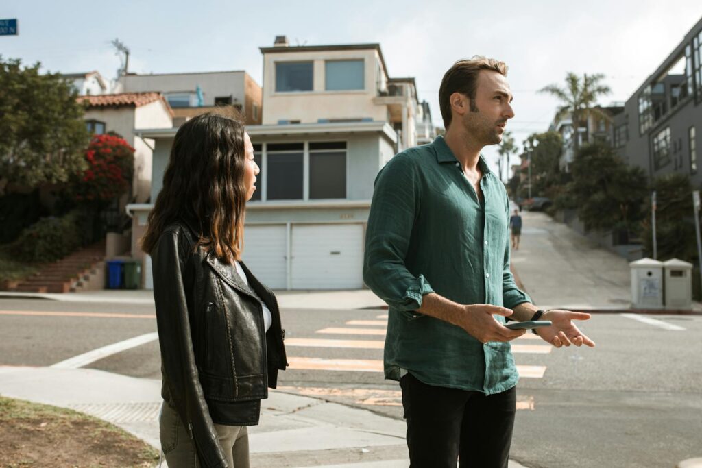 A couple stands on an urban street corner, engaged in a conversation outdoors.
