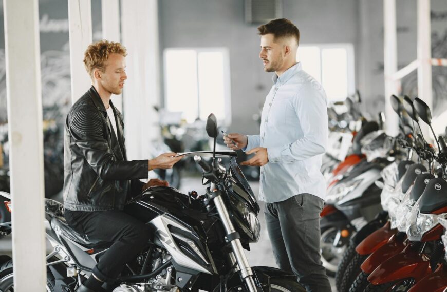 Two men in a motorcycle dealership discussing a potential motorcycle purchase.