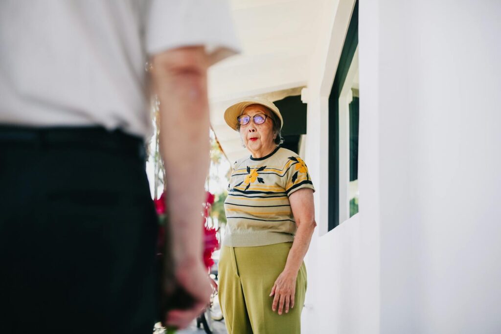 A senior woman is surprised as she receives flowers from a man on a sunny day. Capturing affection and unexpected joy.