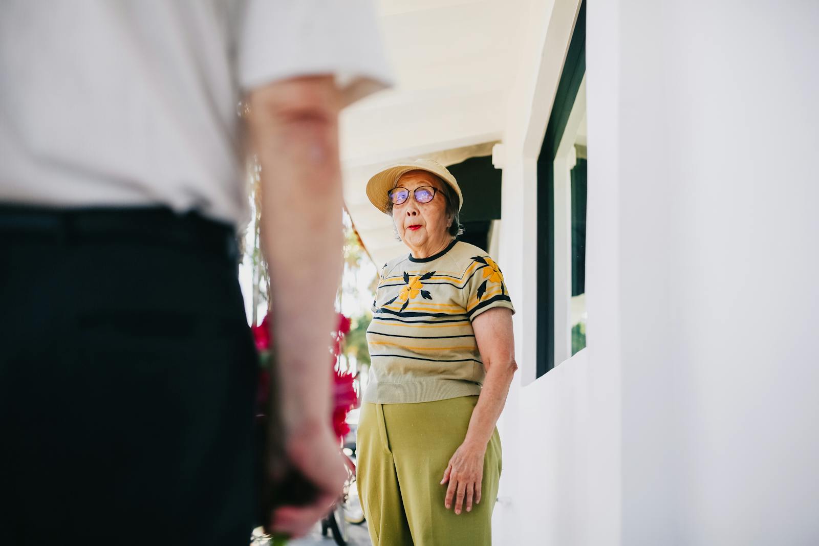 A senior woman is surprised as she receives flowers from a man on a sunny day. Capturing affection and unexpected joy.