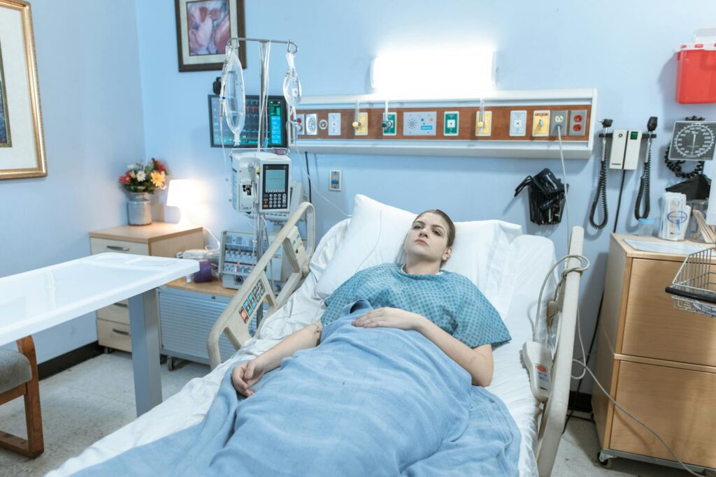 A young woman lies in a hospital bed during her recovery process in a calm, well-equipped room.