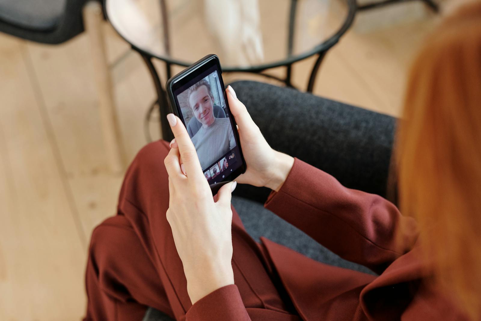 Woman in red suit video calling on smartphone, indoor setting.