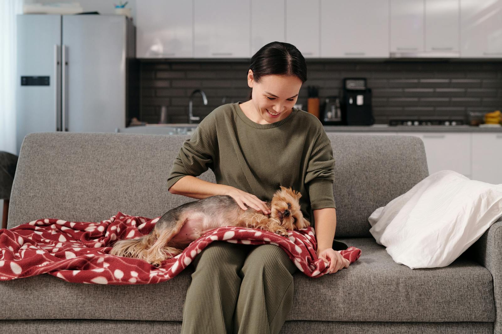 Woman petting a small dog on a cozy couch, enjoying a relaxing moment at home.