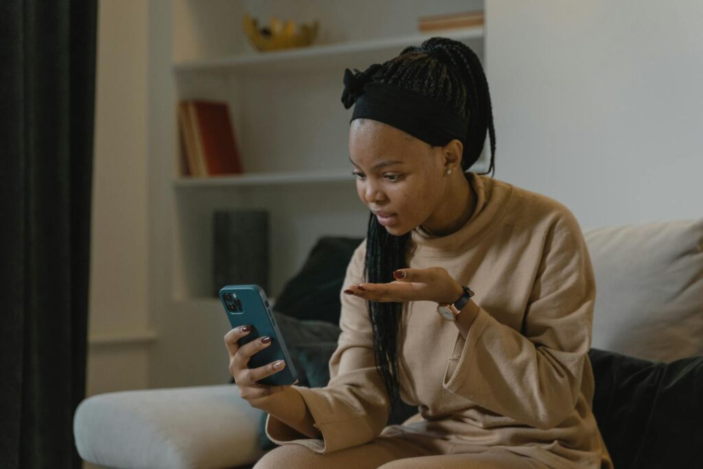 African American woman engaged in video call using smartphone at home, showing a moment of connection.
