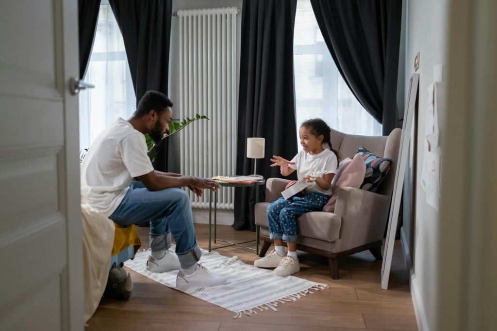 A father and daughter engage in conversation in a cozy indoor setting, fostering family connection.