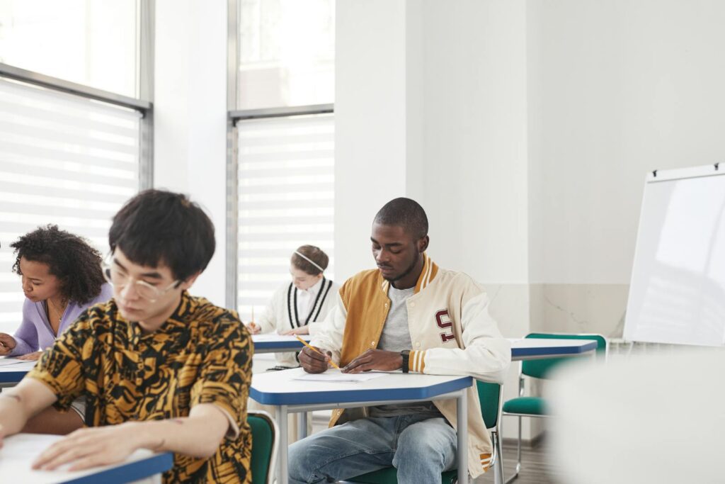 Focused college students in a classroom taking an exam, showcasing diversity and collaboration.