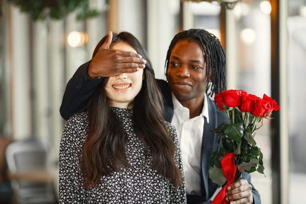 An affectionate surprise with a bouquet of red roses, capturing a joyful couple moment.