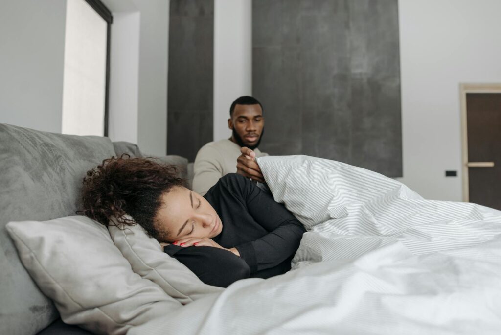 Man comforts his sick wife at home, highlighting care and support.