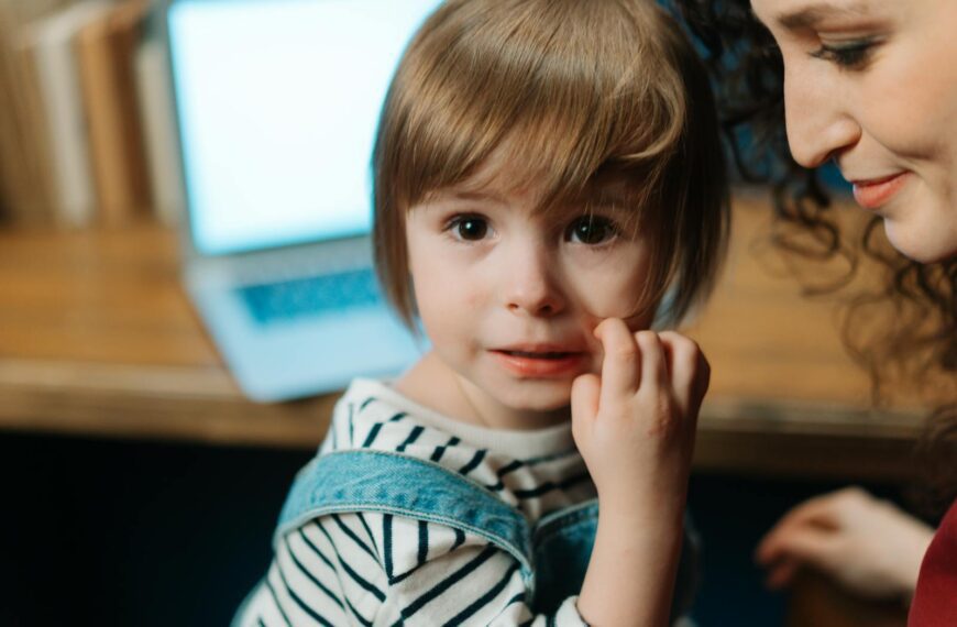 A child with mother near a laptop, depicting a warm family bond indoors.