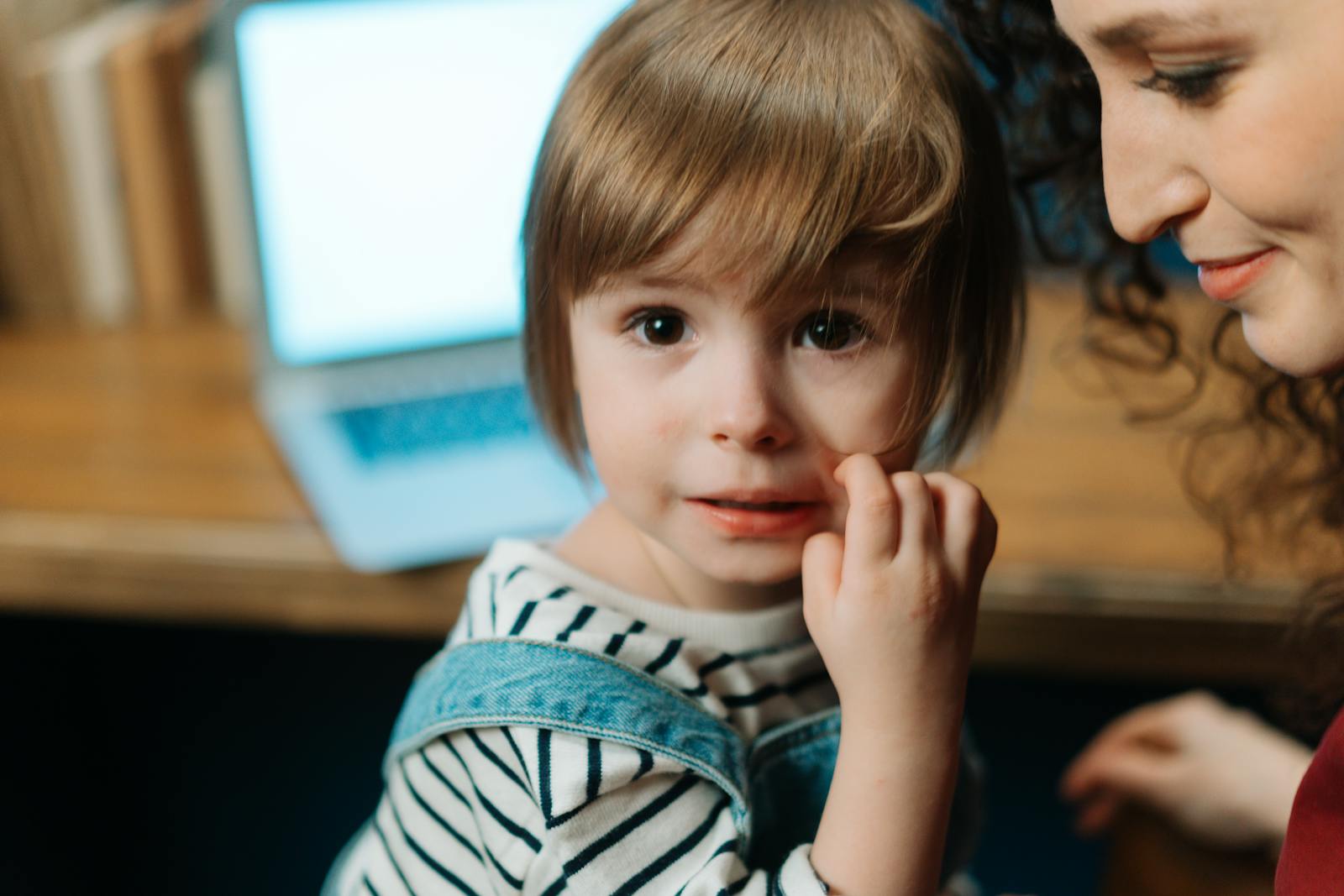 A child with mother near a laptop, depicting a warm family bond indoors.