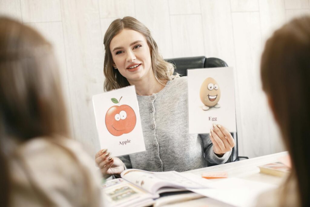 A female teacher uses flashcards to engage young students in a learning activity.