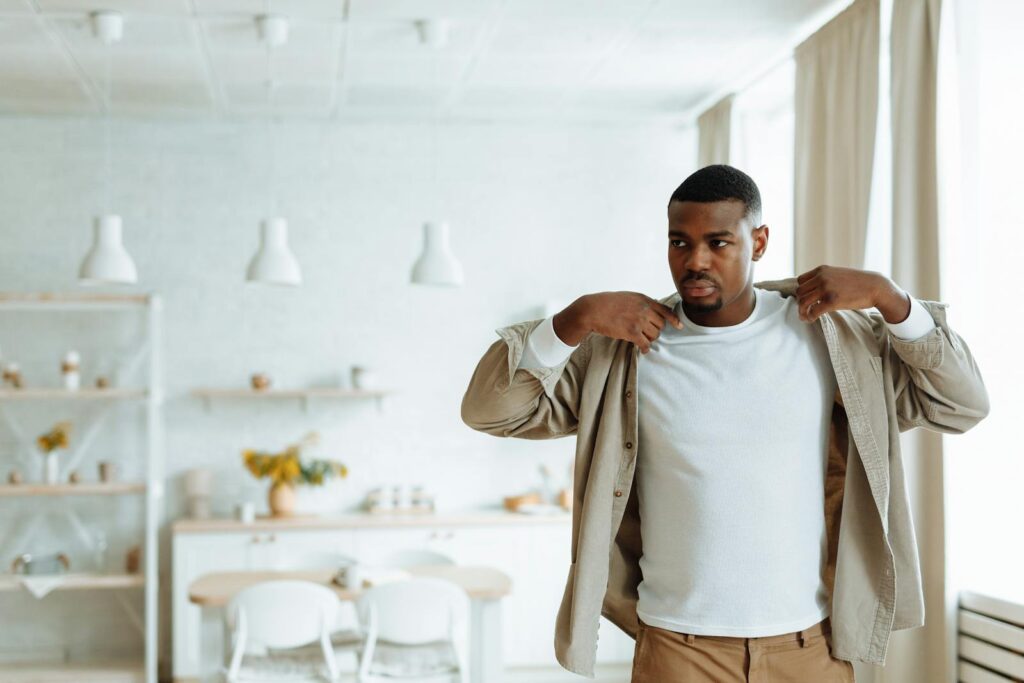 African American man in dining room adjusting shirt, warm and relaxed atmosphere.
