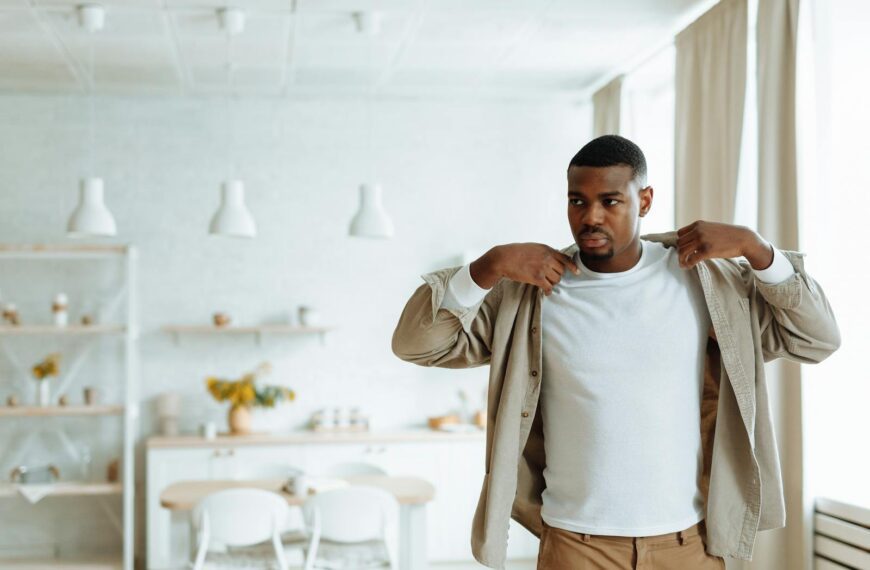 African American man in dining room adjusting shirt, warm and relaxed atmosphere.