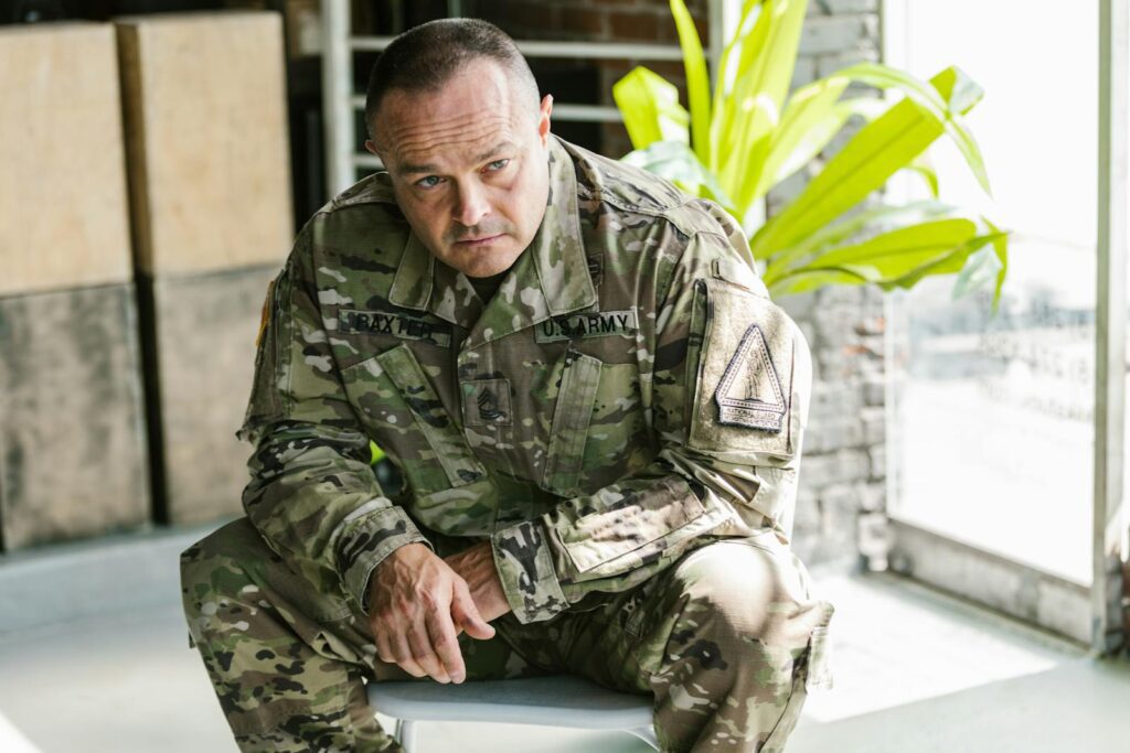 Focused army soldier sitting indoors in military uniform.