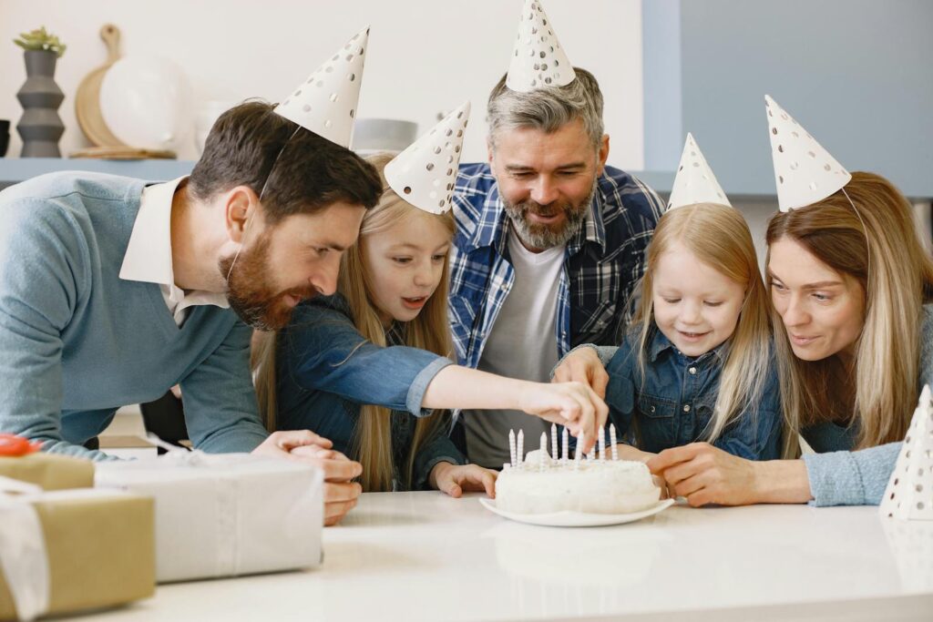 A joyful family gathering around a cake during a birthday celebration indoors.