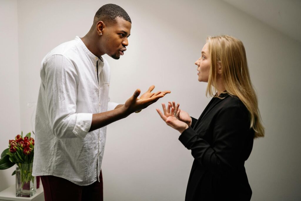 A man and woman engaged in a heated office argument, displaying emotion and intensity.