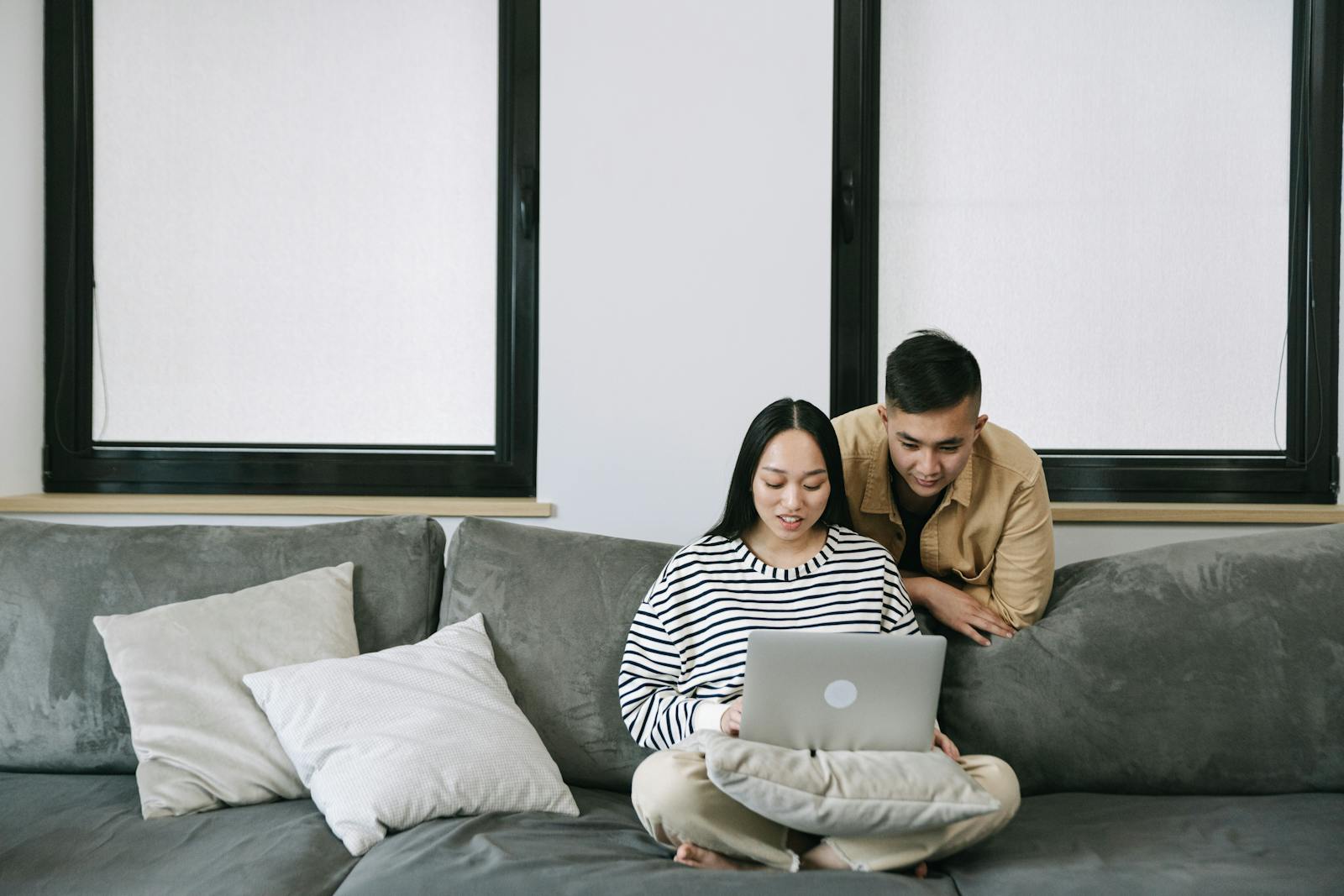 A couple enjoying a cozy moment indoors while using a laptop on the sofa.