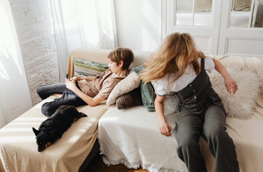 A boy and girl relaxing with their dog on a comfortable living room sofa, enjoying warmth and togetherness.