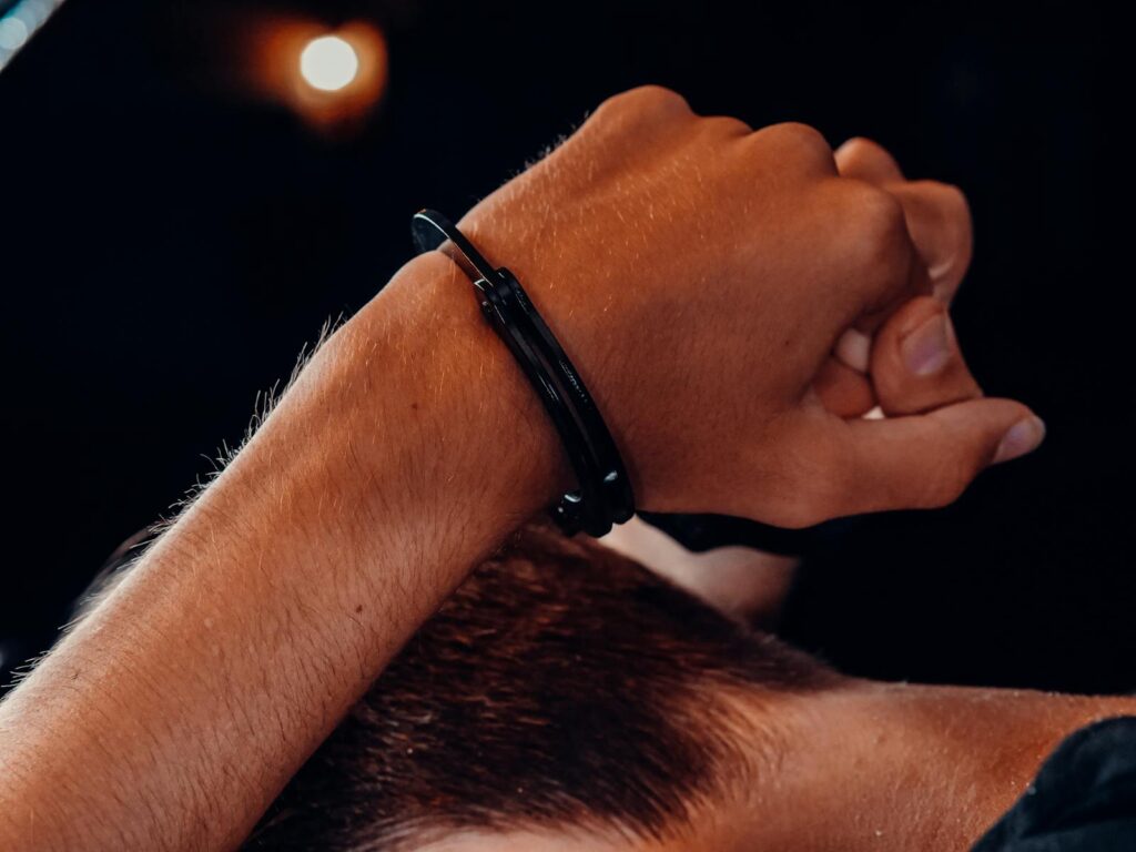 A close-up of a hand in handcuffs against a dark background, depicting a concept of security and restraint.