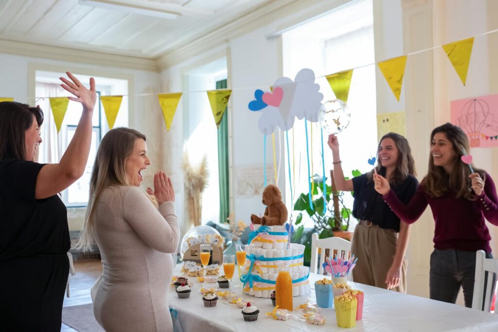 Women celebrating a baby shower with decorations, food, and games indoors.
