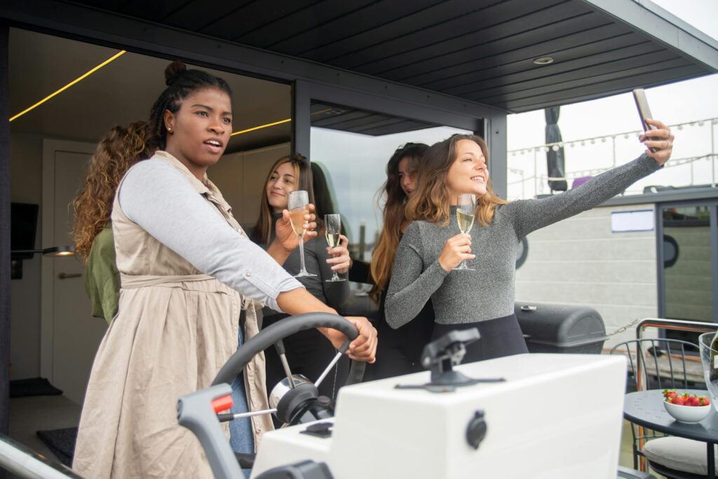 Women enjoying a boat cruise in Portugal with drinks and taking selfies.