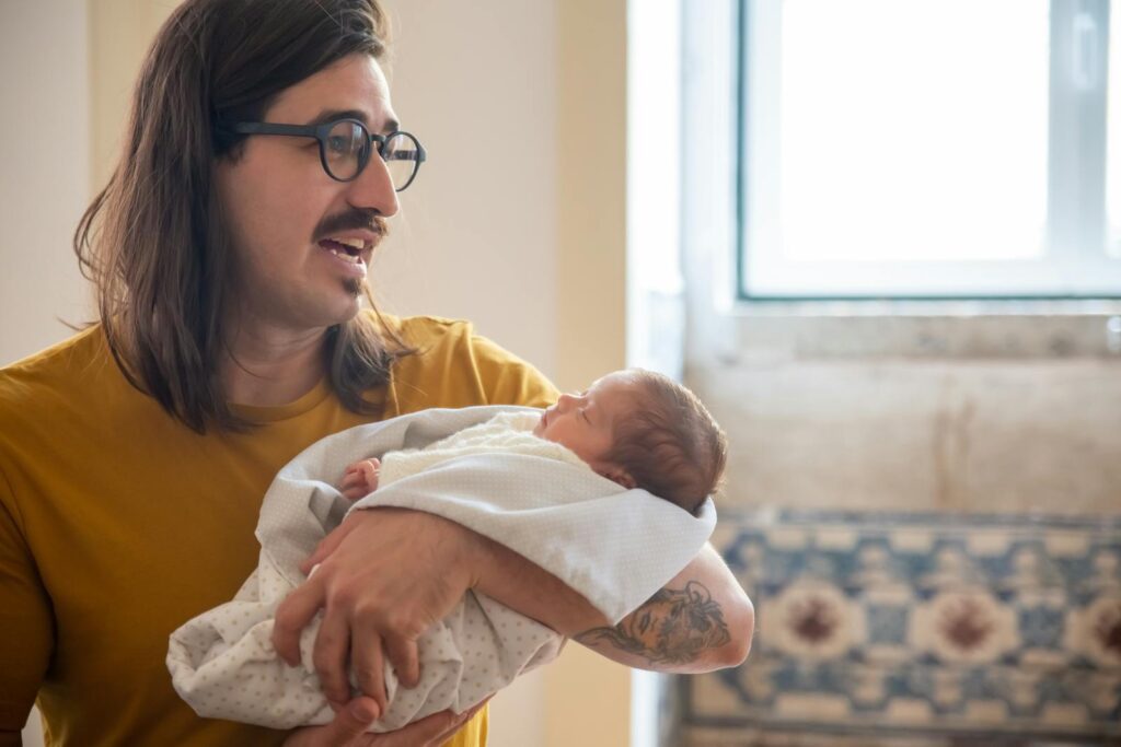A father lovingly holds his newborn baby indoors, creating a warm and joyful atmosphere.