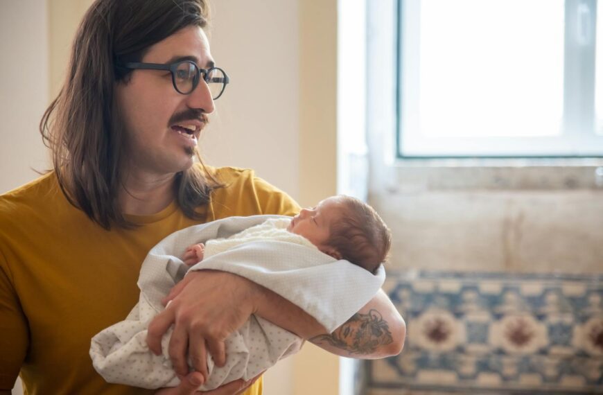 A father lovingly holds his newborn baby indoors, creating a warm and joyful atmosphere.