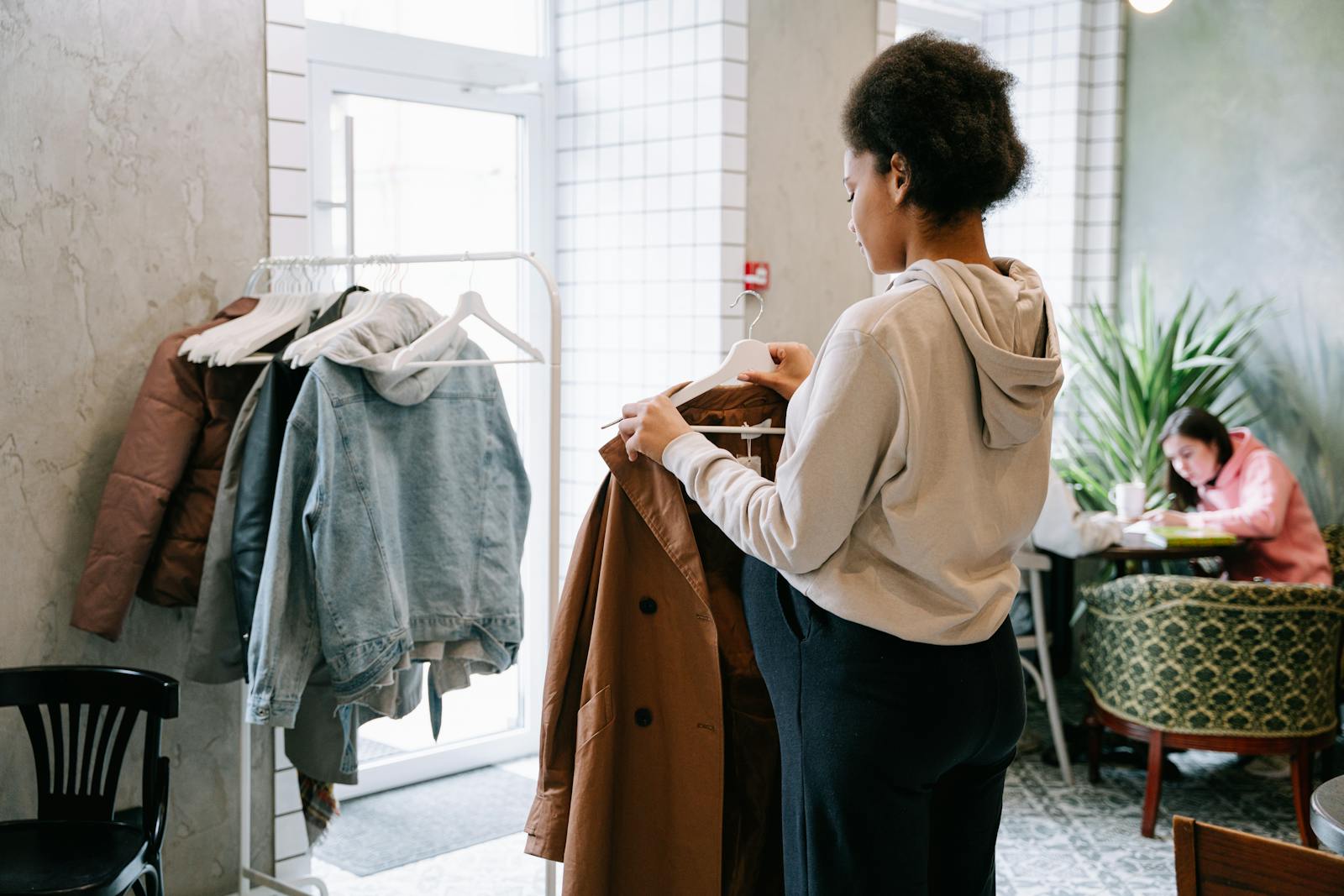 A woman browsing coats indoors, creating a cozy shopping atmosphere.