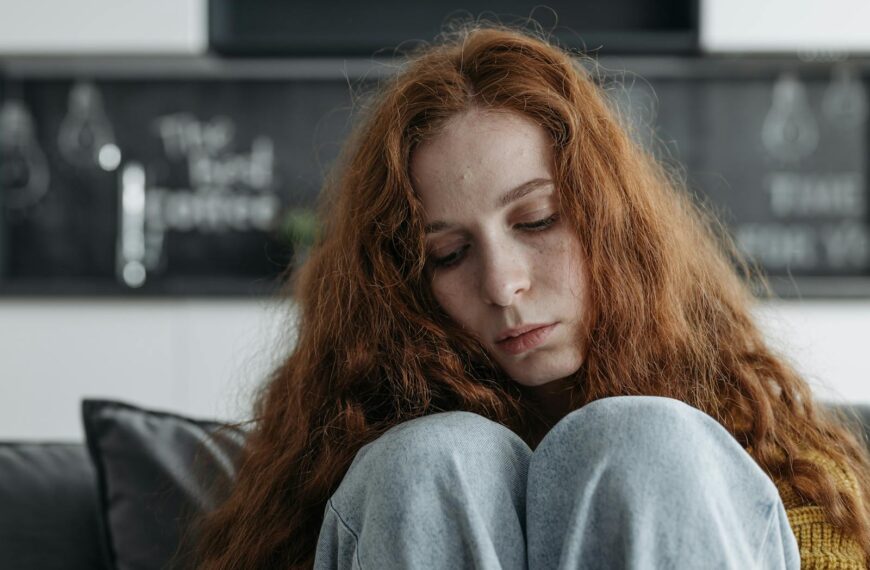 A close-up portrait of a thoughtful woman with red hair, conveying deep emotion and introspection.