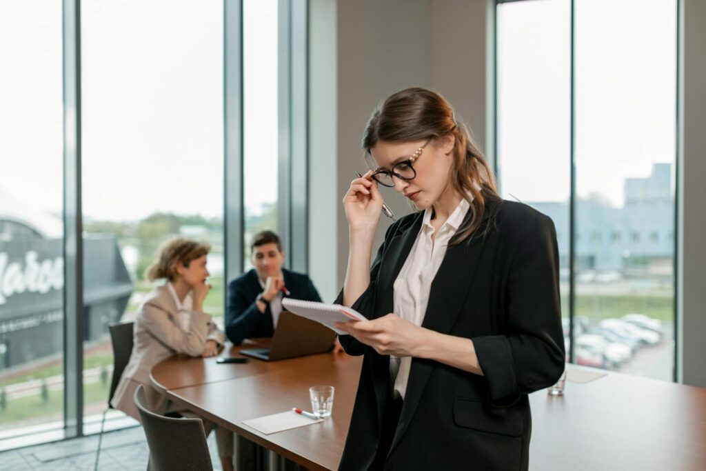 Confident woman reviewing notes leading a business meeting in a modern office setting.
